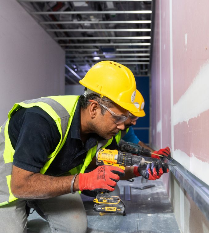 best commercial interior fit out companies abu dhabi person drilling into a wall
